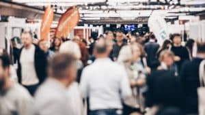 Personas en feria empresarial con stands y marcas en evento profesional